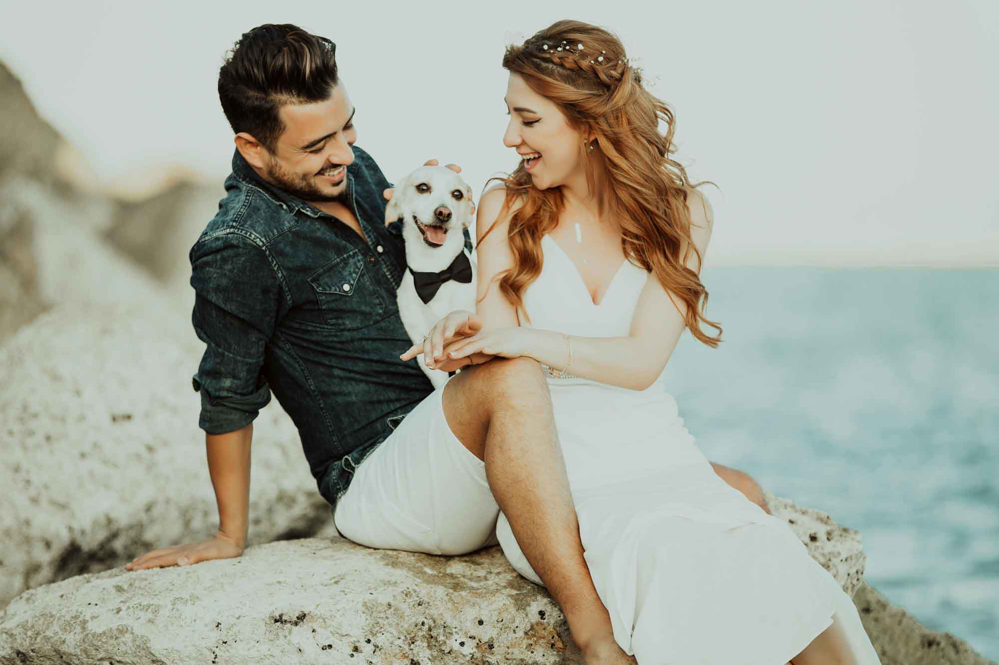 A couple enjoying their engagement photo shoot with their dog at the beach