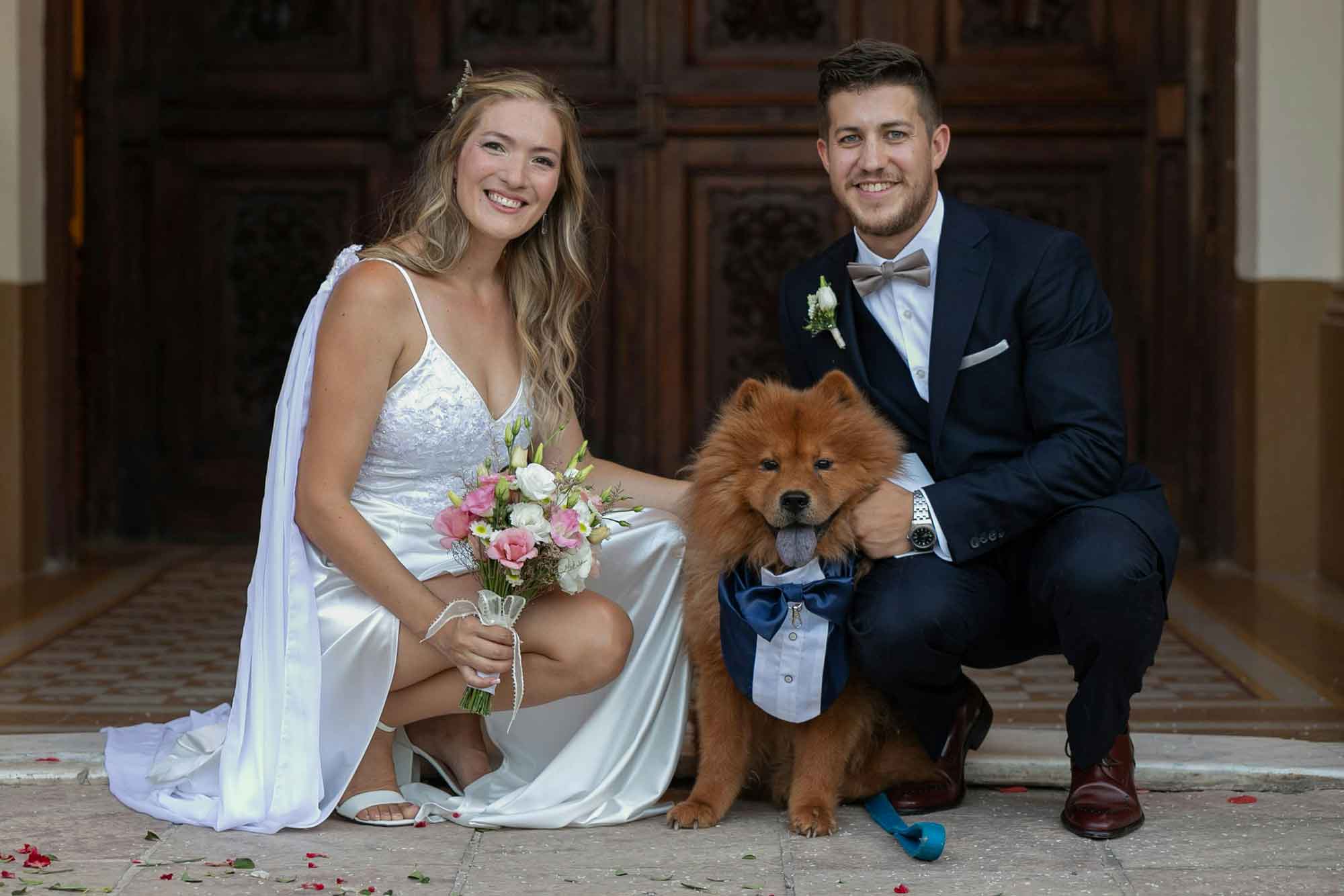 Bride and groom crouching with their dog on their wedding day