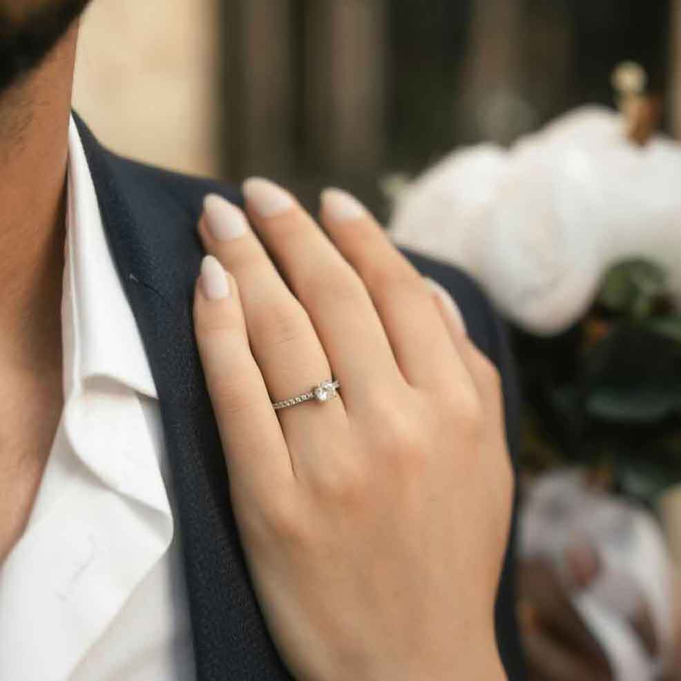woman's hand with engagement ring on man's shoulder