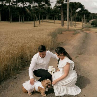 Bridal couple kneeling on dirt road with dog