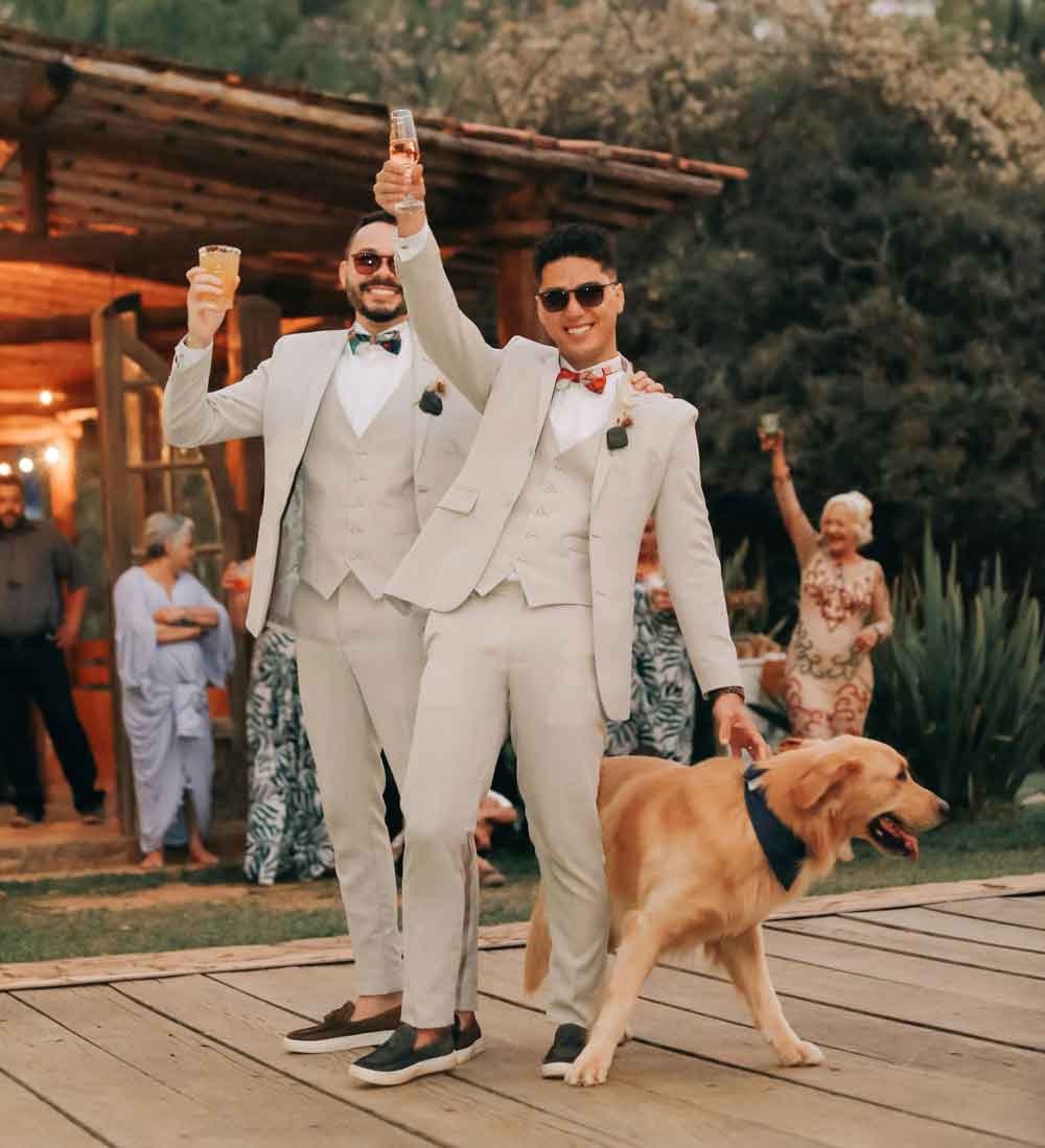two groomsmen raising glasses with dog